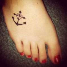 a small tattoo on the foot of a woman with an arrow and heart in it