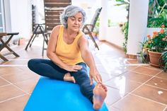 an older woman is sitting on a yoga mat