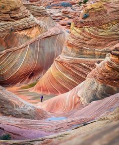 a person standing in the middle of a canyon filled with red and white rocks,