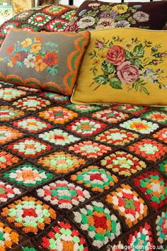 a bed with colorful crocheted bedspread and pillows on top of it