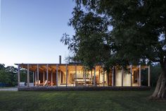 the house is surrounded by large trees and has glass walls to allow natural light into the room