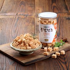 a bowl of tofu next to a jar of tofu on a cutting board