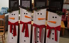 three snowmen made out of shutters with red bows