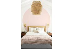 a bedroom with pink walls, white bedding and an upholstered headboard