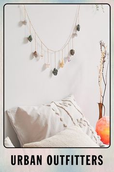 there is a bed with white sheets and beads hanging on the wall above it, next to a vase filled with flowers