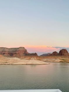 there is a boat on the water near some mountains and sand dunes in the distance