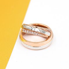 two wedding bands with diamonds on top of each other in front of a yellow and white background