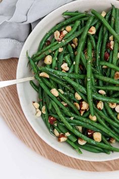 a white bowl filled with green beans and nuts