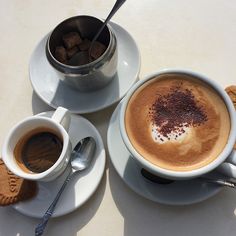 two cups of cappuccino and some cookies on a table