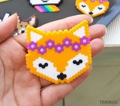 a hand holding a piece of bead art that has been made to look like a fox