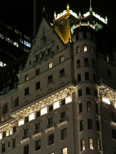 the top of a large building lit up at night with lights shining on it's sides