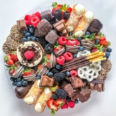 a platter filled with assorted chocolates, strawberries, raspberries and more