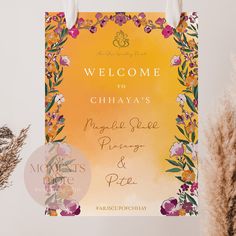 a welcome sign hanging from a wall next to dried flowers