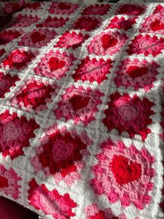 a pink and white crocheted blanket on top of a bed