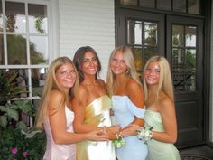 four beautiful young women standing next to each other in front of a building with windows