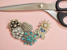 a pair of scissors sitting on top of a table next to some brooches