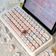 a laptop computer sitting on top of a table covered in pink and white keyboard keys