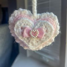 a crocheted heart ornament hanging from a string in front of a window