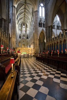 the interior of a large cathedral with pews and checkerboard flooring,