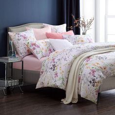 a bed with pink and white comforters in a room next to a blue wall