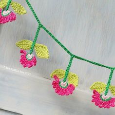 some crocheted flowers are hanging from a line