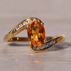 The Fire: Citrine And Natural Diamond Bypass Ring In Yellow Gold. Embrace Elegance With Our Stunning Ring Featuring An Elongated Oval Brilliant-Cut Citrine As Its Centerpiece. The Bypass-Style Shank, Set With Round Brilliant-Cut Natural Diamonds To The North And South, Adds A Touch Of Sophistication. With A Total Diamond Weight Of Approximately 0.10 Carats, This Ring Is Crafted In 14 Karat Yellow Gold. Currently Sized At A Finger Size 6, Adjustments For A Personalized Fit Are Available Upon Request For An Additional Charge. Elevate Your Style With This Timeless Piece. Citrine Engagement Ring Vintage, Citrine Engagement Ring, Citrine Ring Engagement, Elongated Oval, Bypass Ring, North And South, Vintage Engagement Rings, The Fire, Womens Jewelry Rings