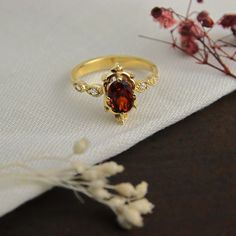 a close up of a ring on a table with flowers in the foreground and a white cloth behind it