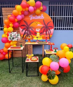 an outdoor party with balloons and desserts on the table in front of a sign