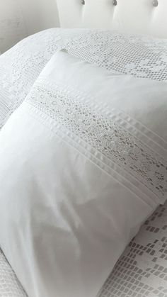 a bed with white sheets and pillows on top of it, next to a headboard