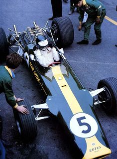 an image of a race car being worked on by men in green shirts and hats