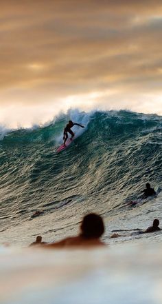 surfers are riding the waves on their surfboards in the ocean at sunset or dawn