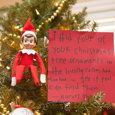 an elf is sitting on top of a christmas tree with a note attached to it