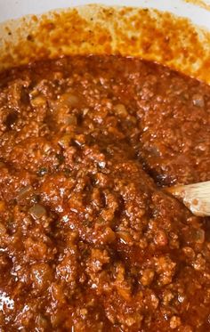 a pot filled with chili sauce and a wooden spoon in it's side dish