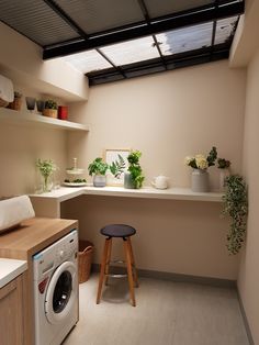 a washer sitting next to a dryer in a kitchen under a skylight