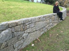 a woman sitting on top of a stone wall