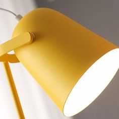 a yellow lamp with a white light on the side and a wall in the background