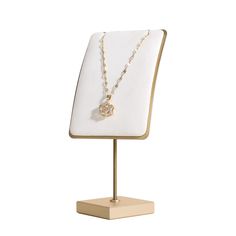 a necklace on a mannequin with a gold chain and a heart charm hanging from it