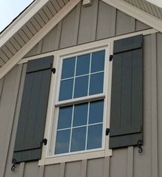 the side of a house with two windows and shutters