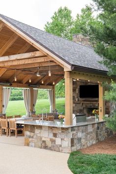 an outdoor kitchen and dining area is shown in this backyard setting with stone fireplaces