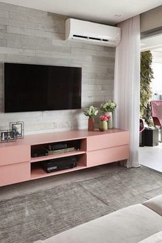 a flat screen tv mounted to the side of a pink entertainment center in a living room