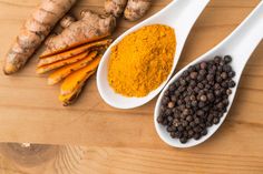 three spoons filled with different types of spices on top of a wooden table next to ginger, turment and black pepper