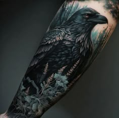 a black and grey tattoo with an eagle on it's arm, surrounded by flowers