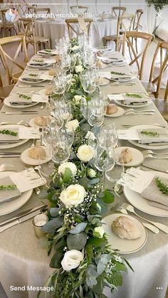 the table is set with white flowers and greenery for an elegant touch to it