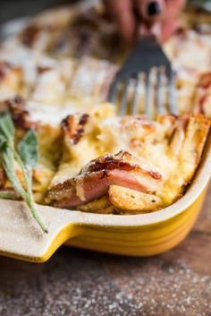 a close up of a plate of food with a fork in it and someone taking a bite out of the casserole