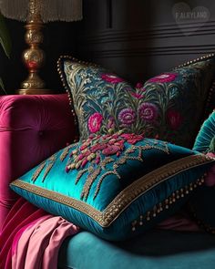 two pillows sitting on top of a blue couch next to a pink chair and lamp