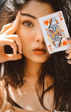 a woman holding up a playing card to her face