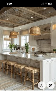 an image of a kitchen with wooden floors and white cabinets in the middle, along with wicker stools at the island