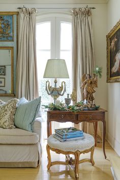 a living room filled with furniture and a lamp on top of a wooden table next to a window