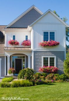 a large gray and white house with flowers in the windows