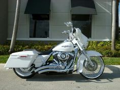 a white motorcycle is parked in front of a building with palm trees on the sidewalk